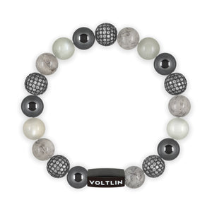 Top view of a 10 mm Gray Sirius beaded stretch bracelet featuring Hematite, Steel Pave, Tourmalinated Quartz, & Moonstone crystal and black stainless steel logo bead made by Voltlin